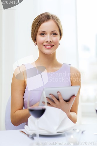 Image of smiling woman with tablet pc computer at resturant