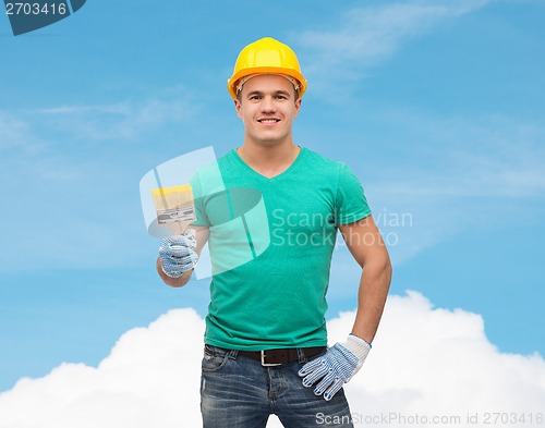 Image of smiling manual worker in helmet with paintbrush