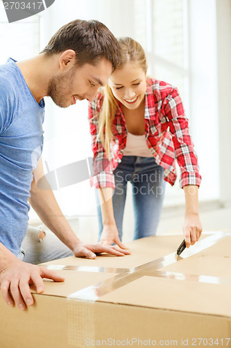 Image of smiling couple opening big cardboard box