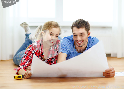 Image of smiling couple looking at blueprint at home