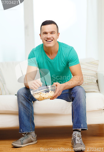 Image of smiling man watching sports at home