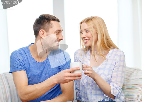 Image of smiling man giving cup of tea or coffee to wife