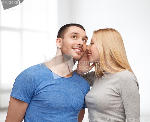 Image of smiling girlfriend telling boyfriend secret