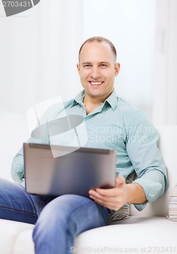 Image of smiling man working with laptop at home