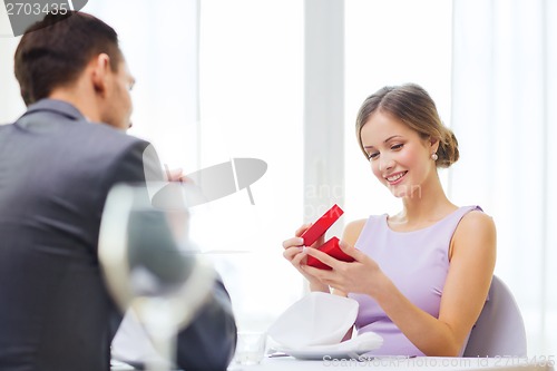 Image of excited young woman looking at boyfriend with box