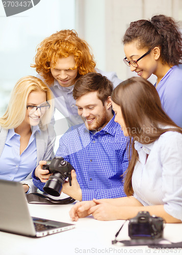 Image of smiling team with laptop and photocamera in office