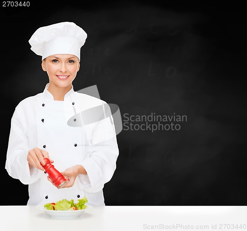 Image of smiling female chef with preparing salad