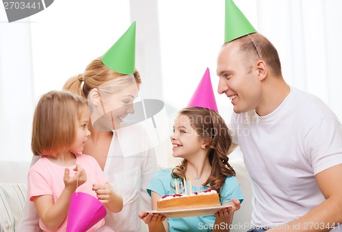 Image of smiling family with two kids in hats with cake