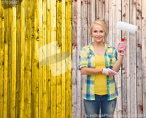 Image of smiling woman in gloves with paint roller