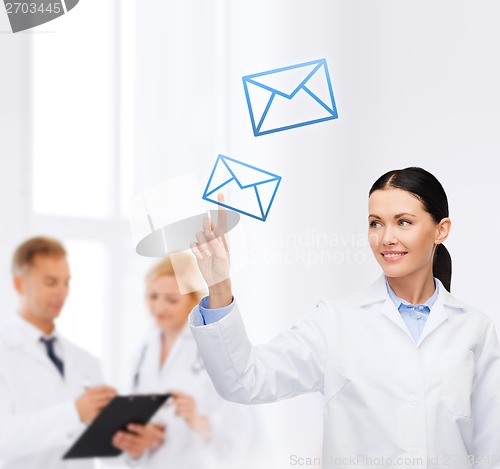 Image of smiling female doctor pointing to envelope