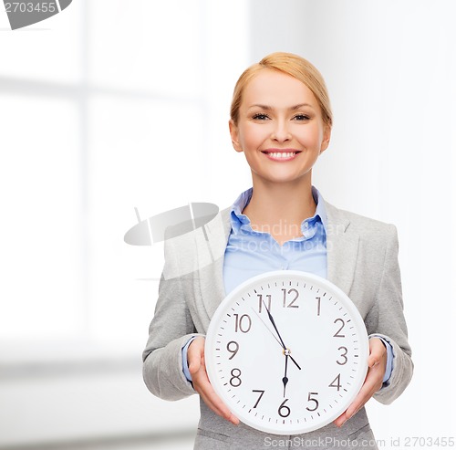 Image of smiling businesswoman with wall clock