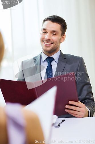 Image of smiling young man with menu at restaurant