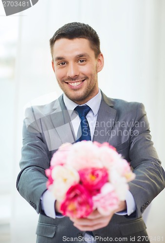 Image of smiling handsome man giving bouquet of flowers