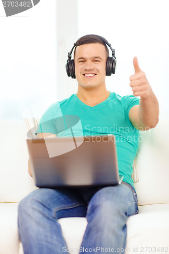 Image of smiling man with laptop and headphones at home