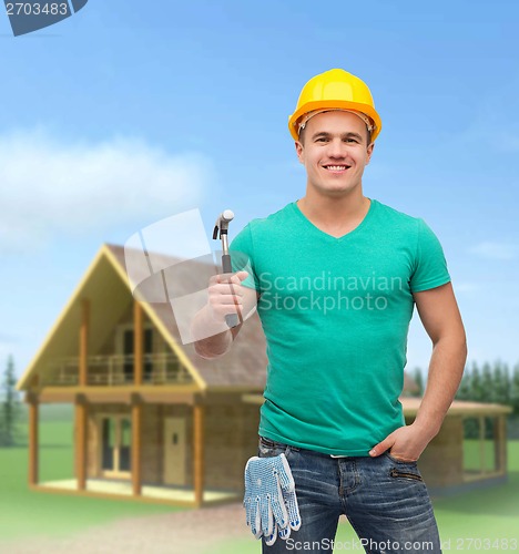 Image of smiling manual worker in helmet with hammer