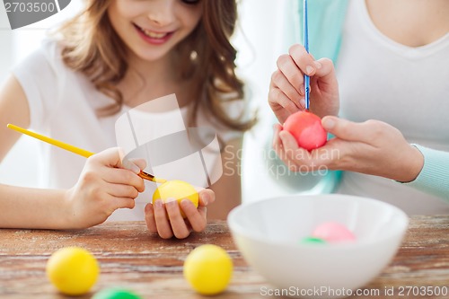 Image of close up of little girl and mother coloring eggs