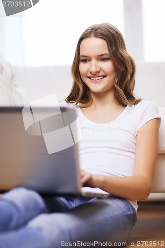 Image of smiling teenage girl with laptop computer at home