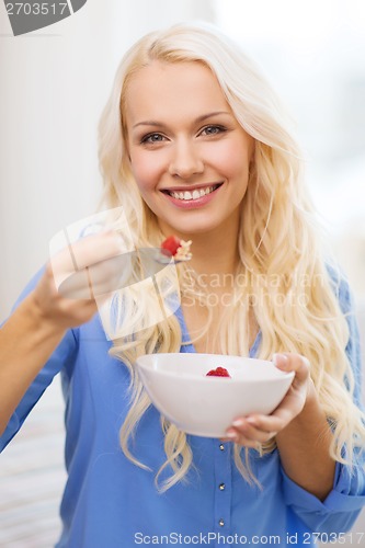 Image of smiling woman with bowl of muesli having breakfast
