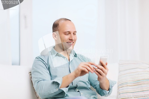 Image of smiling man with smartphone at home