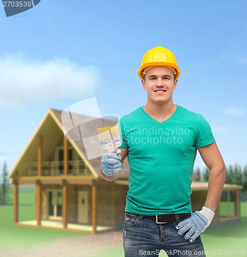 Image of smiling manual worker in helmet with paintbrush