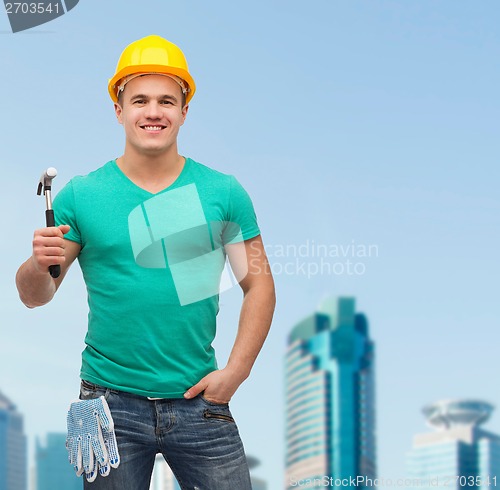 Image of smiling manual worker in helmet with hammer