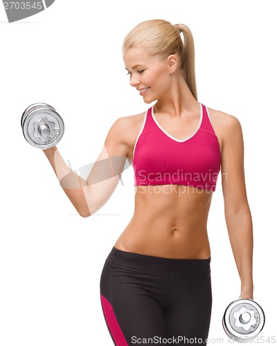 Image of smiling woman lifting steel dumbbell