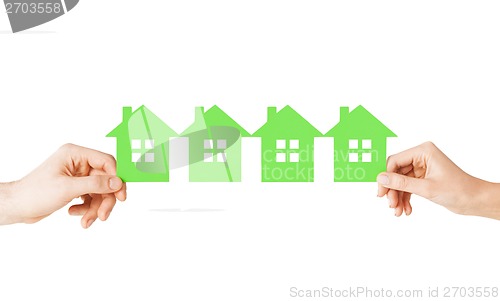 Image of man and woman hands with many green paper houses