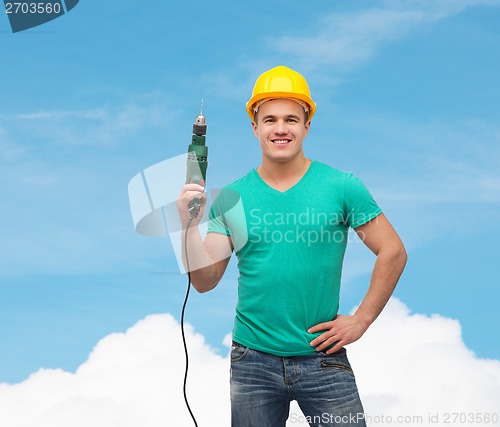 Image of smiling manual worker in helmet with drill machine