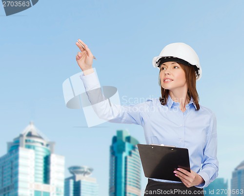 Image of smiling businesswoman in helmet with clipboard