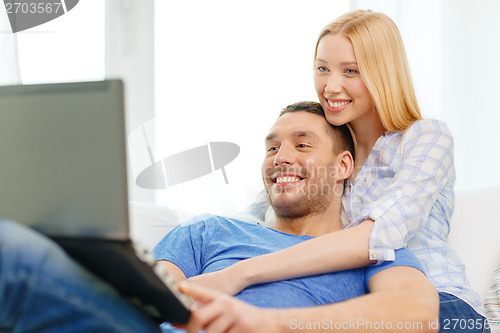 Image of smiling happy couple with laptop at home