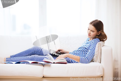 Image of smiling teenage girl with laptop computer at home