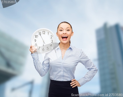 Image of attractive businesswoman with wall clock