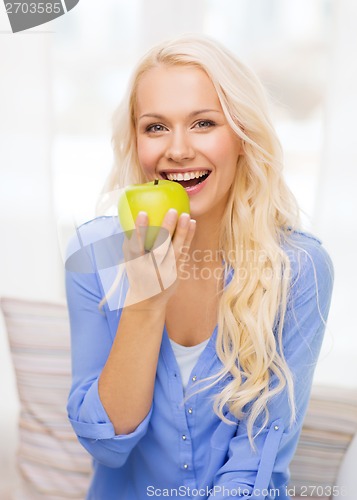 Image of smiling woman with green apple at home