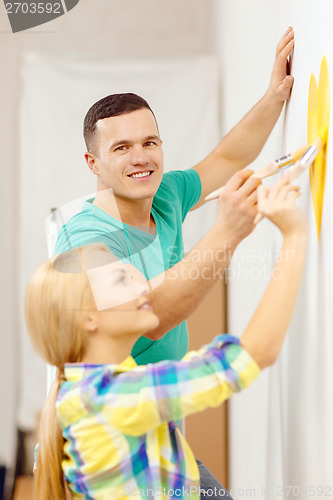 Image of smiling couple painting small heart on wall