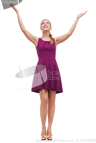 Image of smiling young woman in dress waving hands