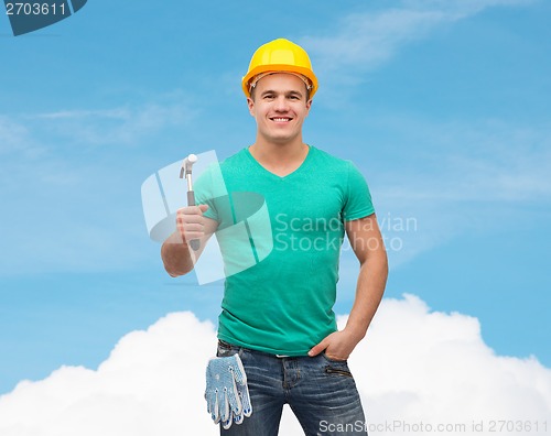 Image of smiling manual worker in helmet with hammer