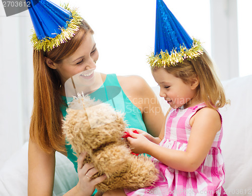 Image of mother and daughter in blue hats with teddy bear