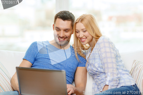 Image of smiling happy couple with laptop at home