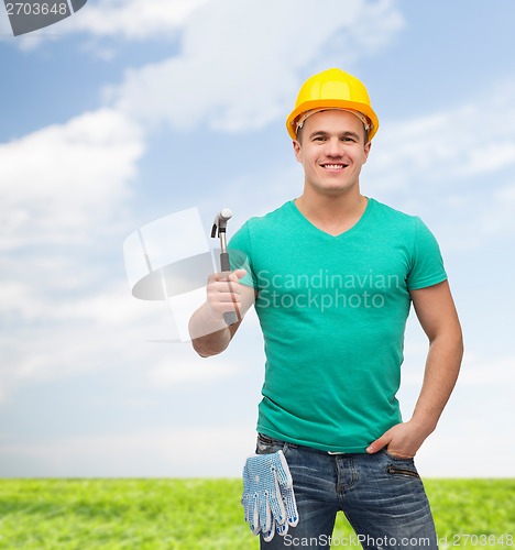 Image of smiling manual worker in helmet with hammer