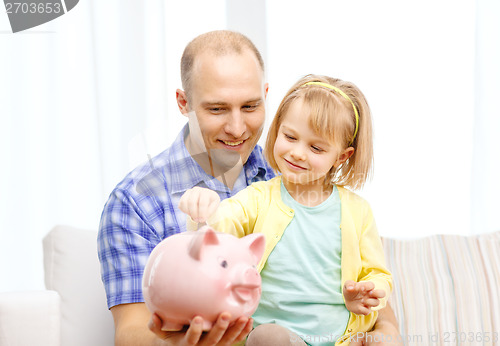 Image of happy father and daughter with big piggy bank