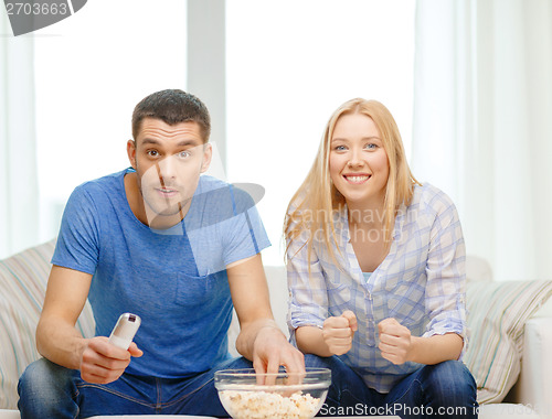 Image of smiling couple with popcorn cheering sports team