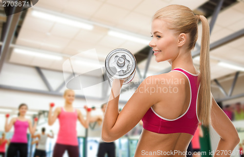 Image of smiling woman with heavy steel dumbbell