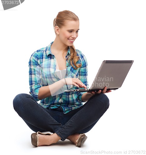 Image of smiling woman with laptop sitting on floor