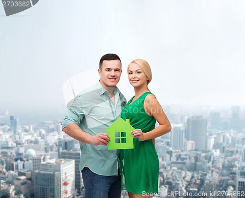 Image of smiling couple holding green paper house