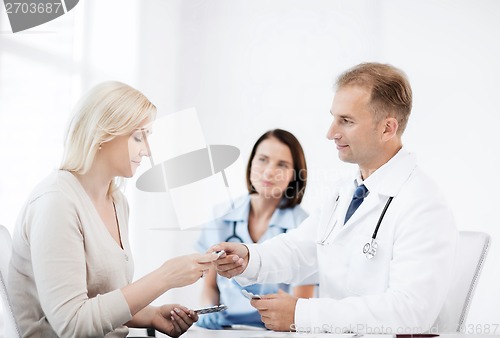 Image of doctor giving tablets to patient in hospital