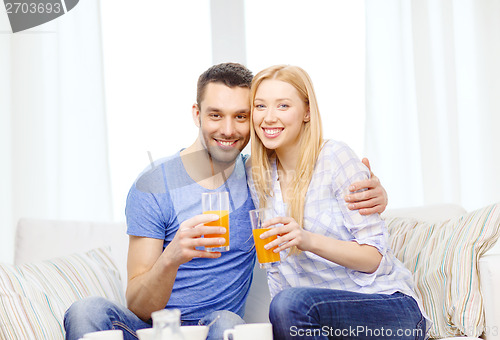 Image of smiling happy couple at home drinking juice