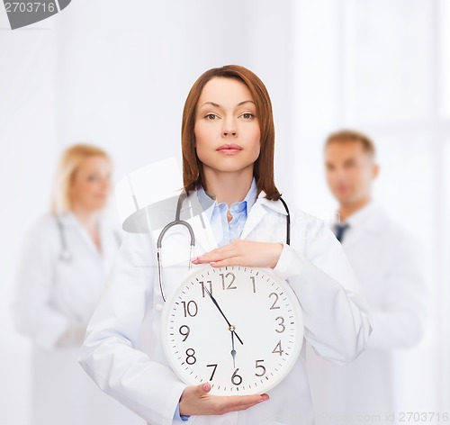 Image of calm female doctor with wall clock