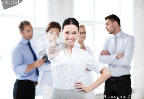 Image of businesswoman in office showing thumbs up