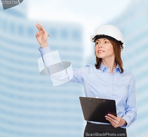 Image of smiling businesswoman in helmet with clipboard