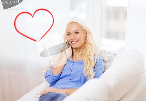 Image of smiling woman with smartphone at home